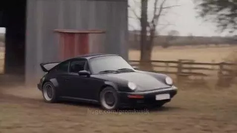 Black Porsche 911 embedded in a tree trunk after a crash on a dirt path.