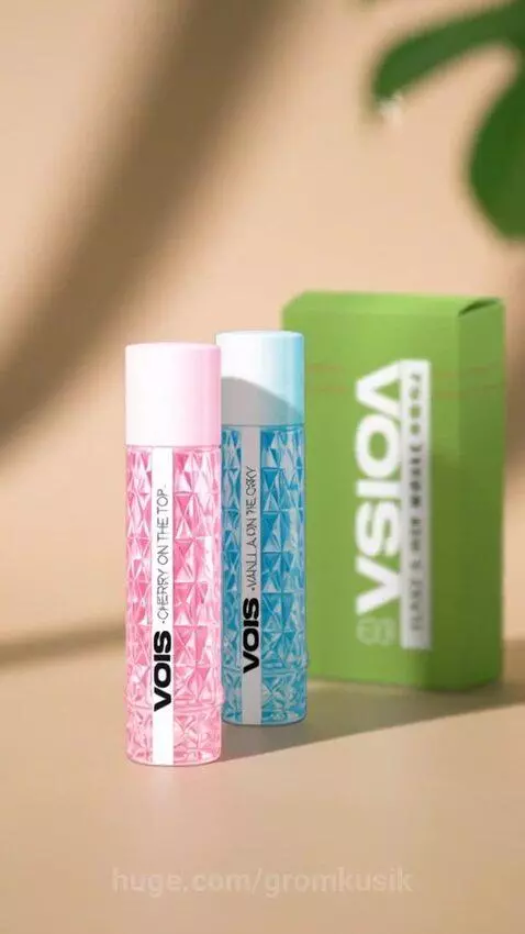 Two VOIS cosmetic bottles, one pink 'Cherry on the Top' and one blue 'Vanilla on the Okey', with geometric patterns.