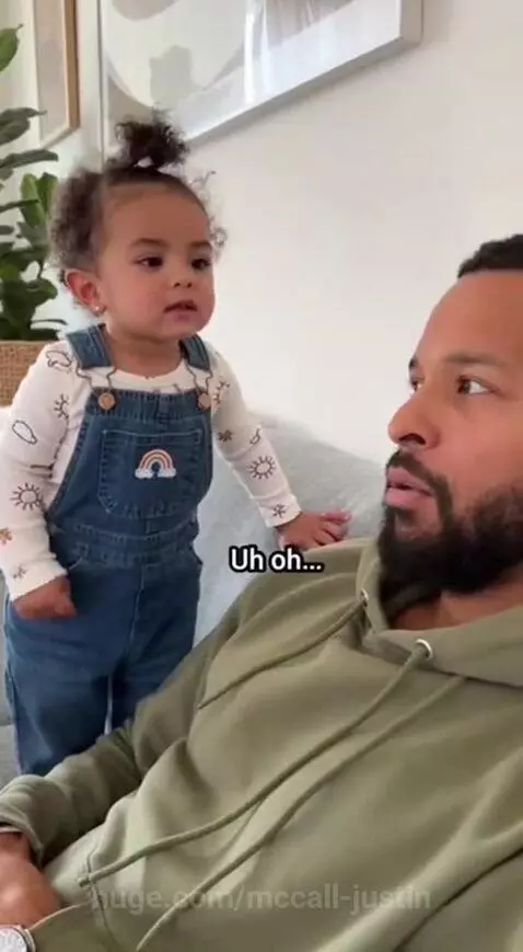A baby in overalls asks a man in a hoodie who he loves more, her or her mommy.