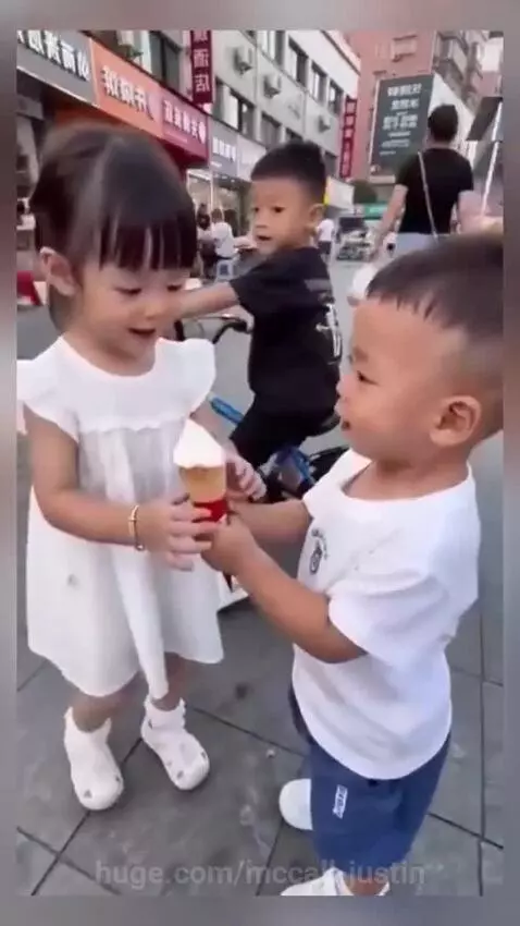 A young boy crying intensely after a girl licks his ice cream cone.