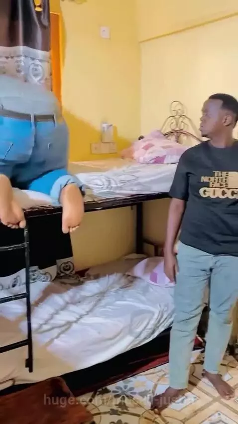 A large man falls onto a bunk bed as the top bunk collapses under his weight.