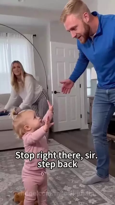 Toddler holding stuffed animal, sternly refusing a hug from dad without chicken nuggets.