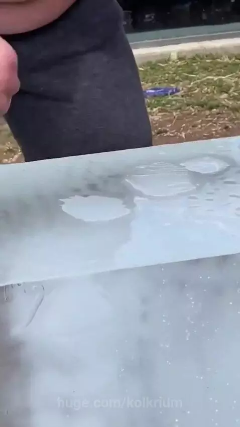 A gorilla punches a large ice cube, shattering it, while a crowd watches in amazement.