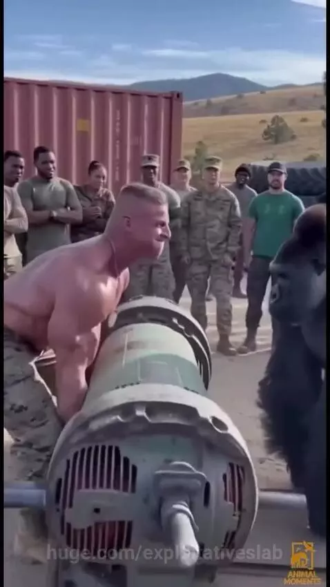 A gorilla in a suit lifts a large industrial motor over its head while a soldier and military personnel watch in amazement.