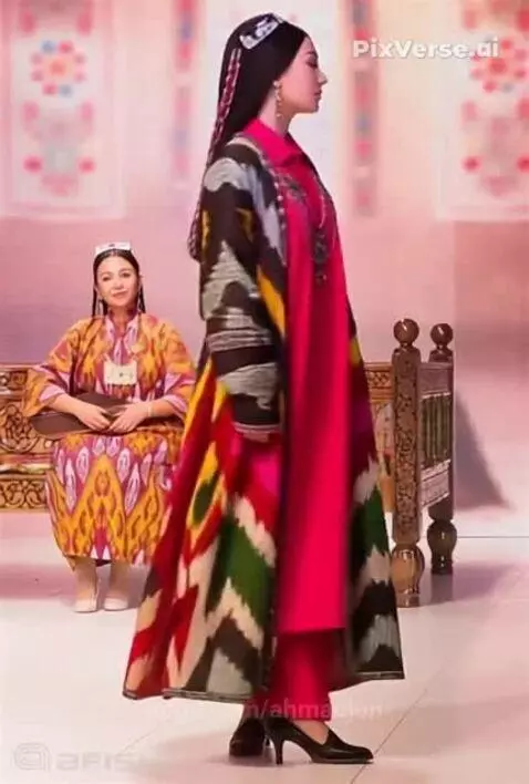 Model wearing a colorful traditional Uzbek ikat coat and pink dress on a stage.