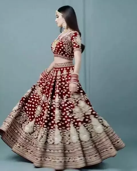 Woman in a maroon and gold embroidered Indian bridal lehenga choli, showcasing the dress with a spin.