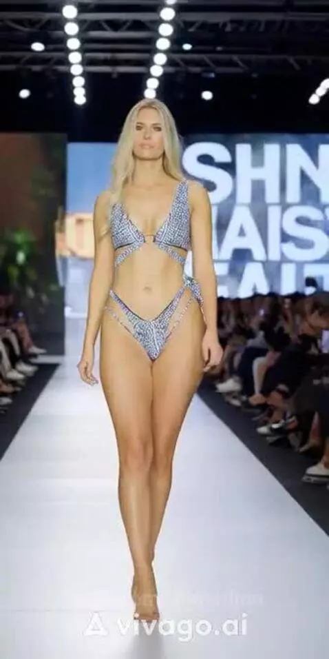Model with blonde hair walking on a fashion runway in a black and white geometric bikini and clear heels.
