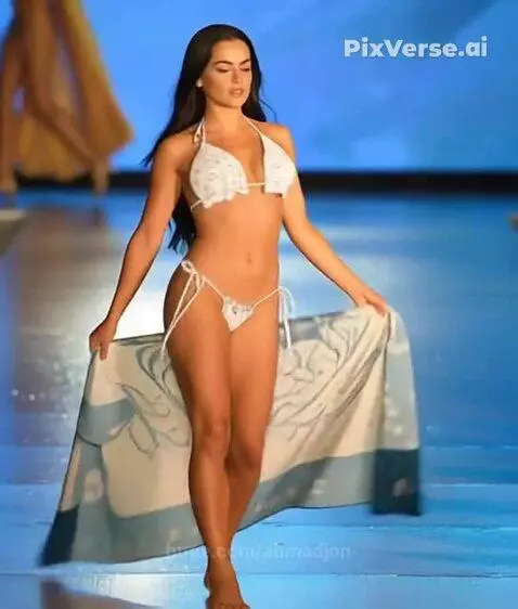 Model with long dark hair walks a runway in a white patterned bikini and matching sarong.
