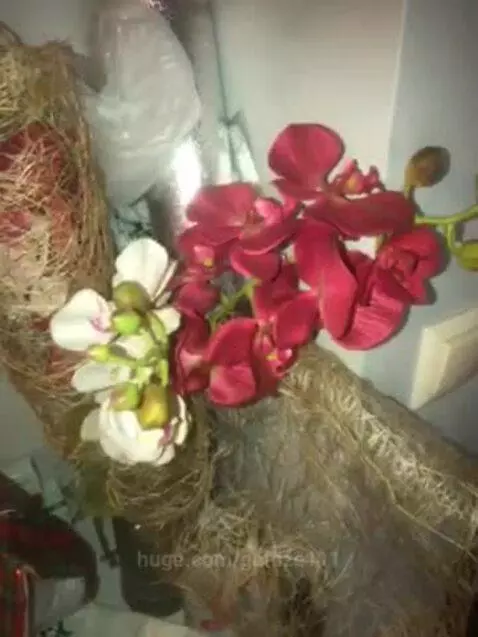 Close-up of two artificial orchid bouquets, one white and one red/pink, wrapped in natural fiber.