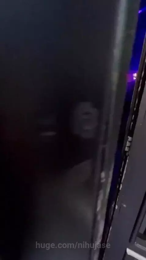 Dimly lit nightclub interior with people dancing under blue and purple lights, featuring a woman in a silver top and another in a blue dress.