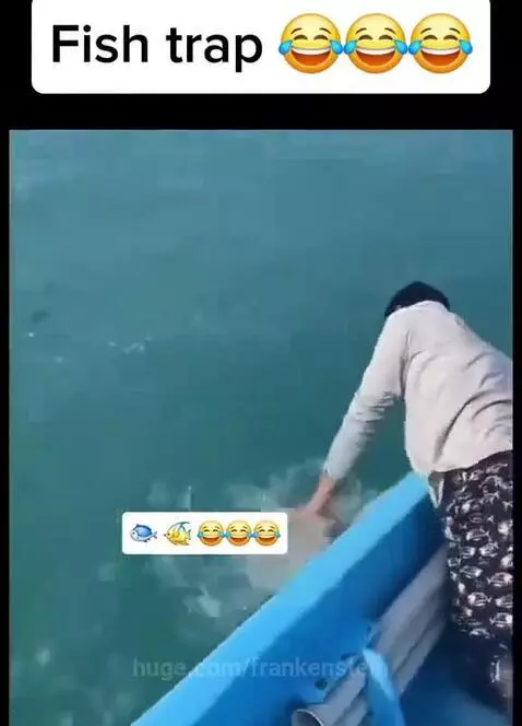 Man on boat surprised by a pufferfish he caught, which is inflated and spiky.