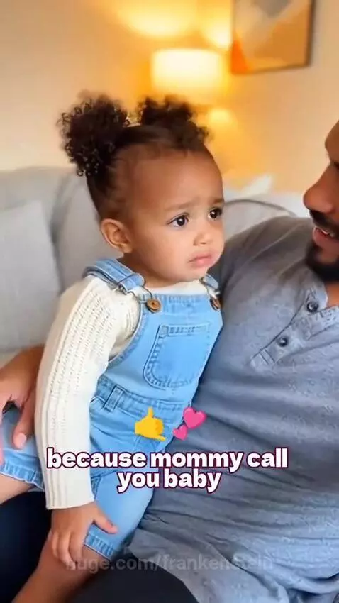 Young child with curly hair in buns asks dad if he's her brother due to mom calling him 'baby'.
