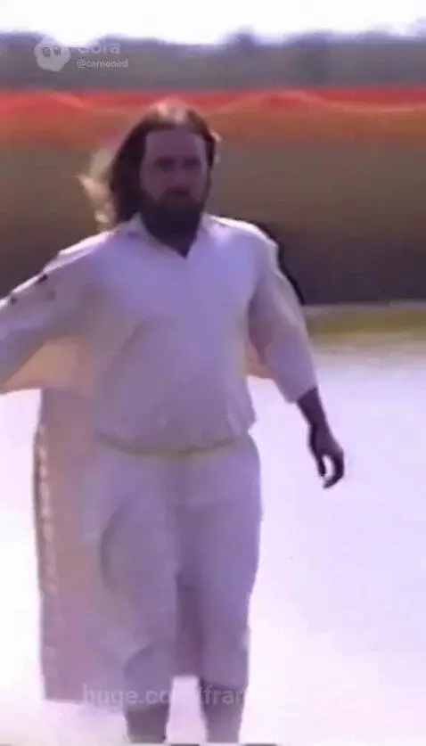 Man in white robe sliding into water and appearing to walk on the surface.