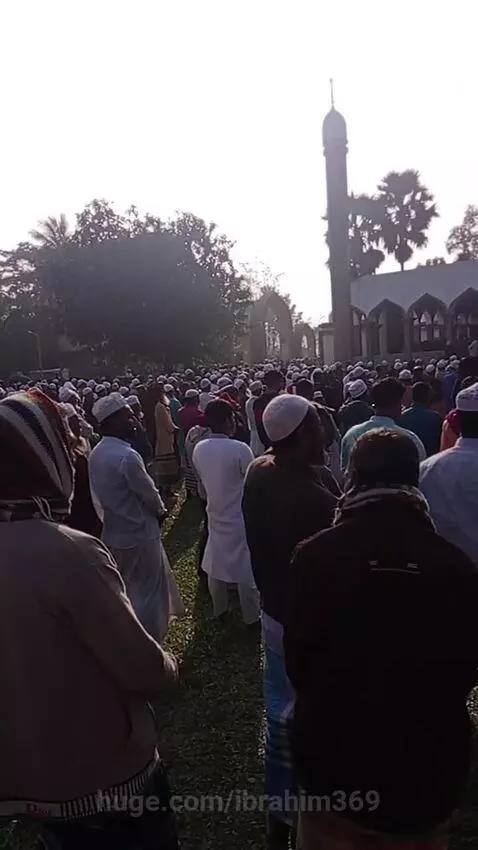 Muslim men gathered for religious ceremony at Chishtinagar Khanqah Chishtia with mosque in background.
