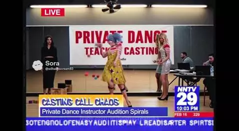 A clown with blue pigtails and yellow overalls performs amidst colorful balls and blocks during a chaotic dance audition.