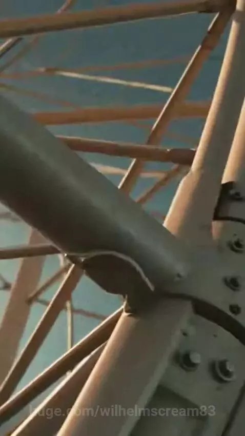 A Ferris wheel collapsing on a crowded tropical beach during a severe storm.