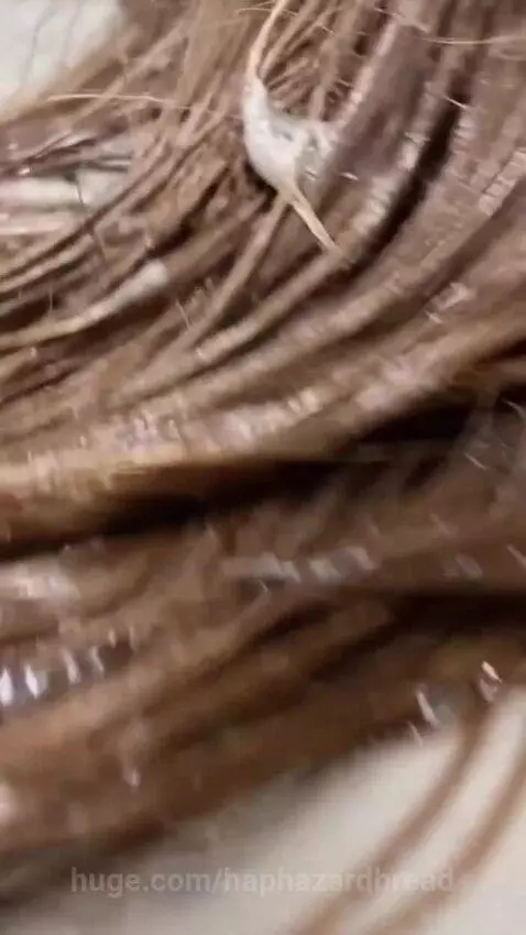 Person with long, wet hair lying on a flooded public restroom floor, smiling at the camera.