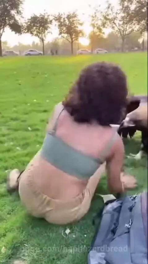 Woman distressed as a large bird aggressively pulls down her green crop top, exposing her chest.