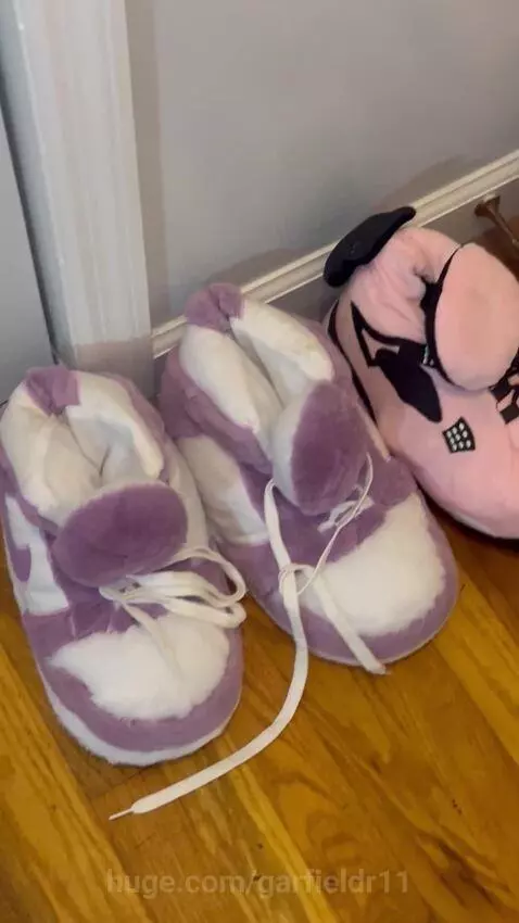 Collection of red Jordan sneakers and plush sneaker-themed slippers on a wooden floor.