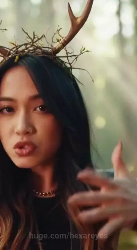 Young adults with antlers and nature costumes dancing energetically in a sunlit forest.