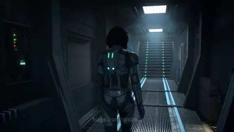 A person in a grey and black futuristic armored suit with blue glowing accents walks down a metallic corridor with blue and green lights.