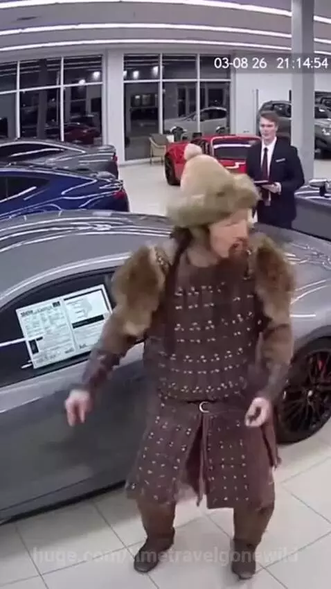 Man in Mongolian attire looking confused at a sports car engine, asking about horses.