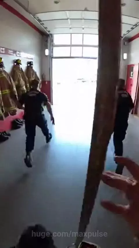 Firefighters quickly donning gear and running towards a fire truck after an alarm sounds.