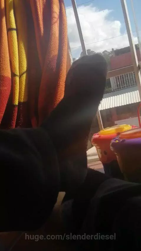 Low-angle view of a person's silhouetted leg and foot in front of a window, with colorful toys nearby.