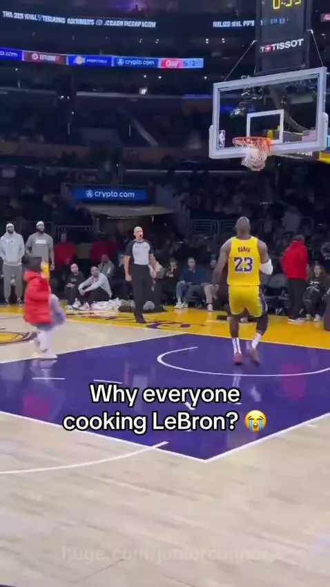 LeBron James playfully guarded by a dog on a basketball court, with kids also present.