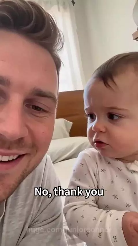 A baby looking at their dad, who is laughing. The baby's expression suggests they just said something funny.