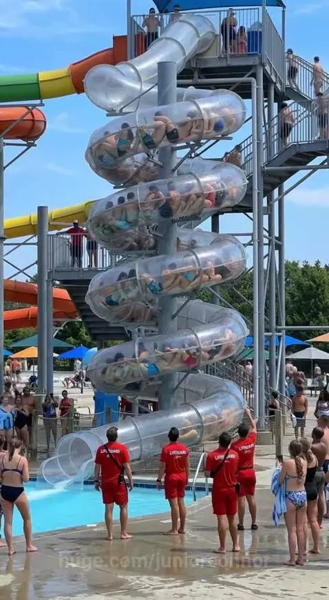 Large group of people stuck inside a clear, spiral water slide at a water park.