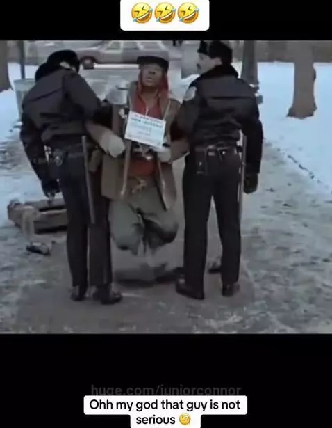 Two police officers watch a man in worn clothes perform a dramatic act as a homeless veteran in the snow.