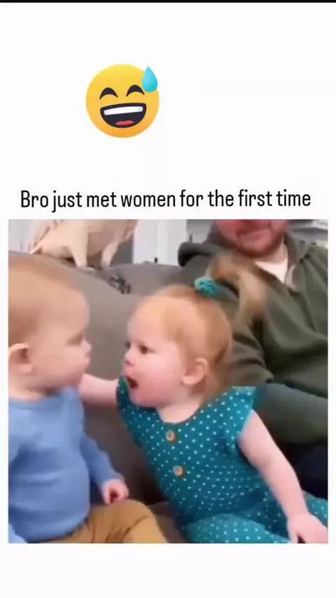Baby boy with a surprised expression looks at a baby girl touching his face.