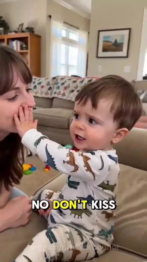 A toddler in a dinosaur onesie pushes away an adult's face, smiling as he claims to have a girlfriend.