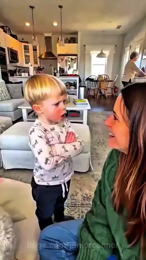 Young boy with blonde hair talking to his mom about too many kisses from grandma.