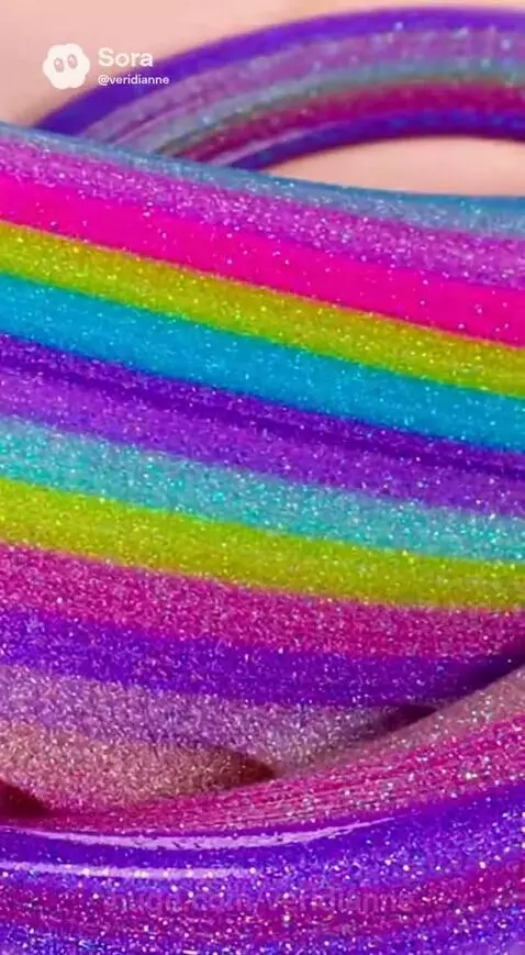 Close-up of rainbow glitter slime with distinct stripes of pink, blue, green, yellow, and purple, sparkling and swirling.