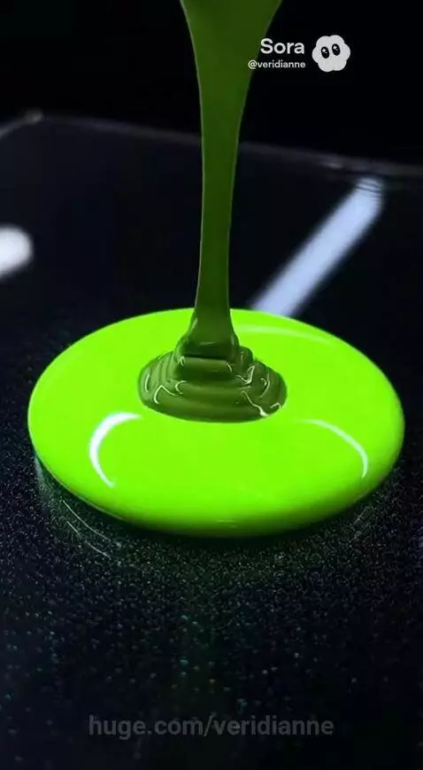 Close-up of neon green paint being poured, creating a circular puddle with swirling patterns as other colors are added.