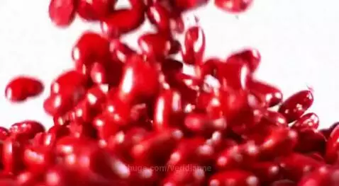 Shiny red cinnamon heart candies falling and splashing into a bubbly liquid.