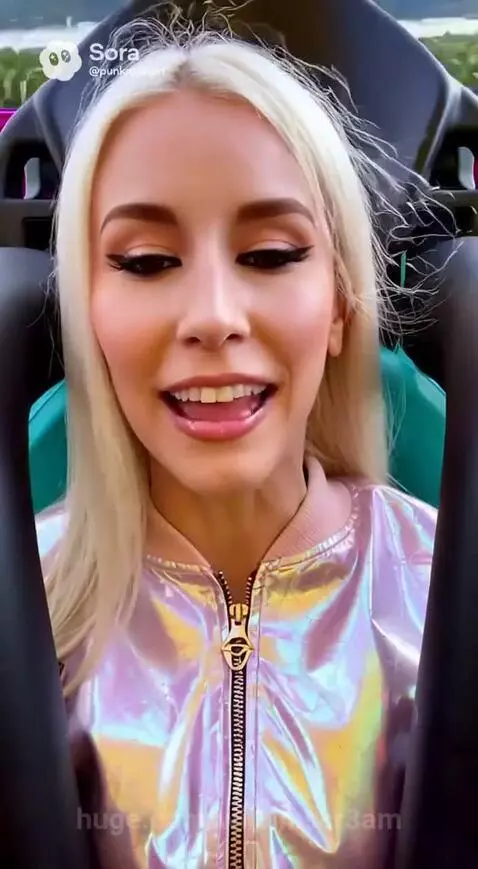 Young woman with blonde hair in a pink jacket on the V-Fall Tower amusement ride, looking excited.