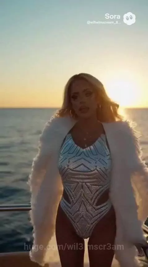Woman in sparkly silver swimsuit and fur coat on a yacht, holding champagne, with ocean and sunset background.