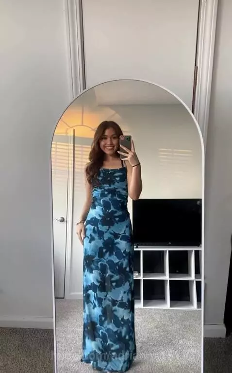 Young woman smiling in an aqua blue bikini after transitioning from a floral dress.