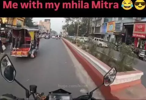 First-person view of a motorcycle navigating a busy street in India, with vehicles and buildings visible.