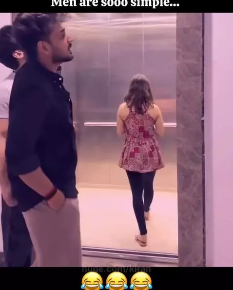 Two men awkwardly enter an elevator and position themselves around a woman focused on her phone.