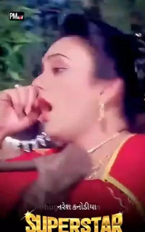 Couple in traditional Indian attire dancing romantically outdoors with trees and foliage.