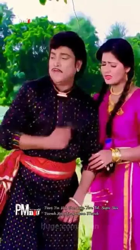 Couple in traditional Indian attire singing and dancing romantically outdoors.