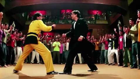 Bruce Lee in a yellow gi fights Neo in a black suit with a high kick in a cheering arena.