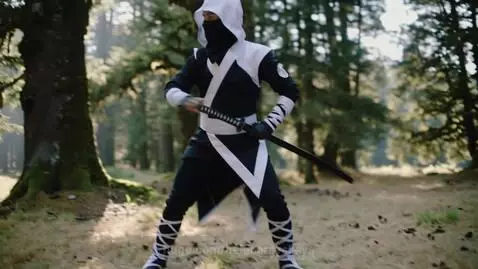 Ninja in black and white costume performing martial arts with a katana in a forest setting.