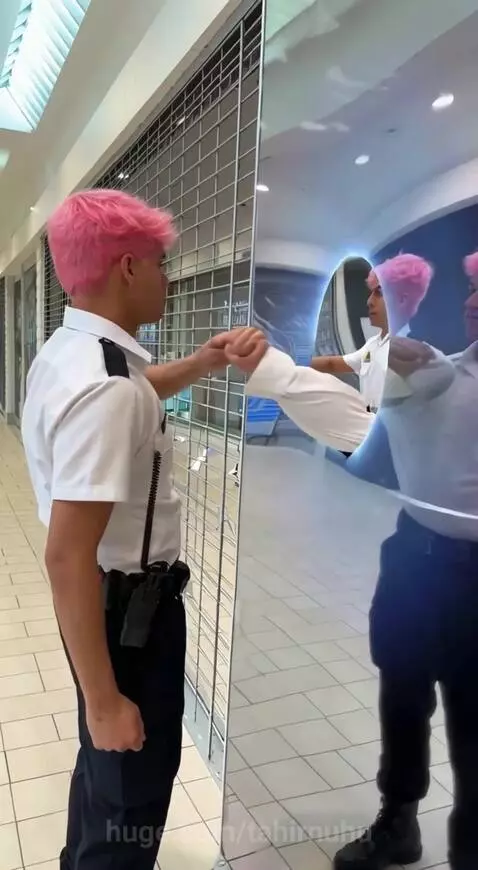 Mall cop with pink hair interacts with a mirror, his reflection emerges as a separate person from a blue portal.