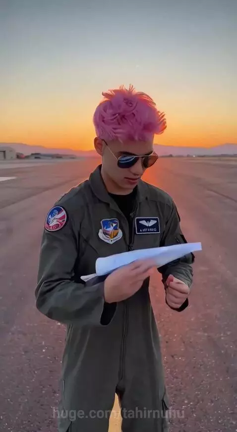 Person in flight suit launches paper airplane that transforms into an F-16 jet flying into the sunset sky.