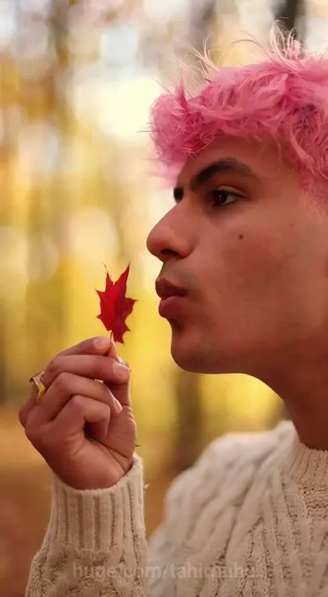 Man in autumn forest releases a glowing fire bird that transformed from a maple leaf.